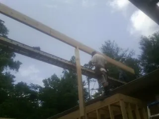 Carpenter setting a ridge beam over a new addition frame — Ice Dam Removal by Roofing Brothers in Benton